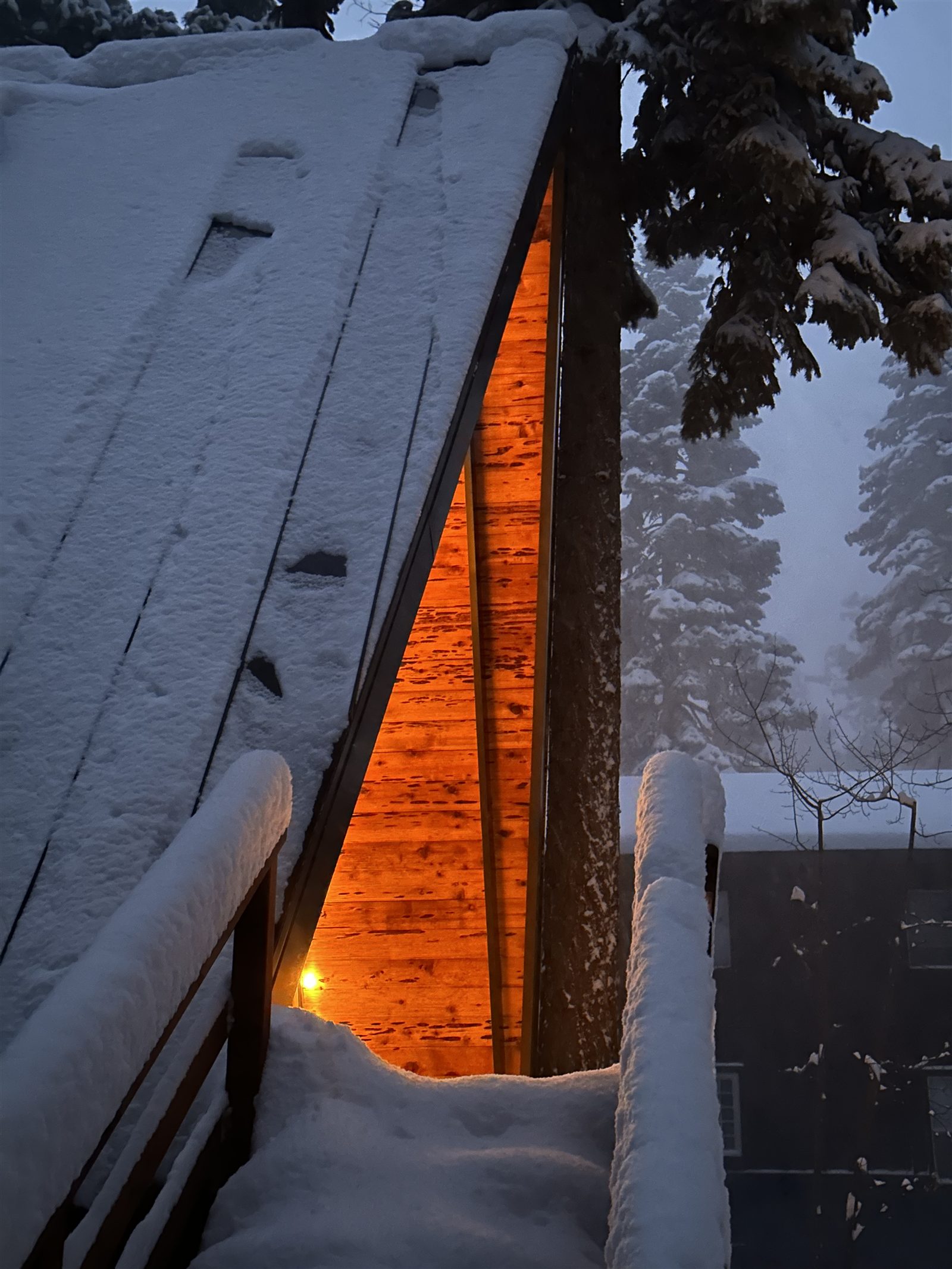 Warm light glowing from the eaves in the snow at dusk