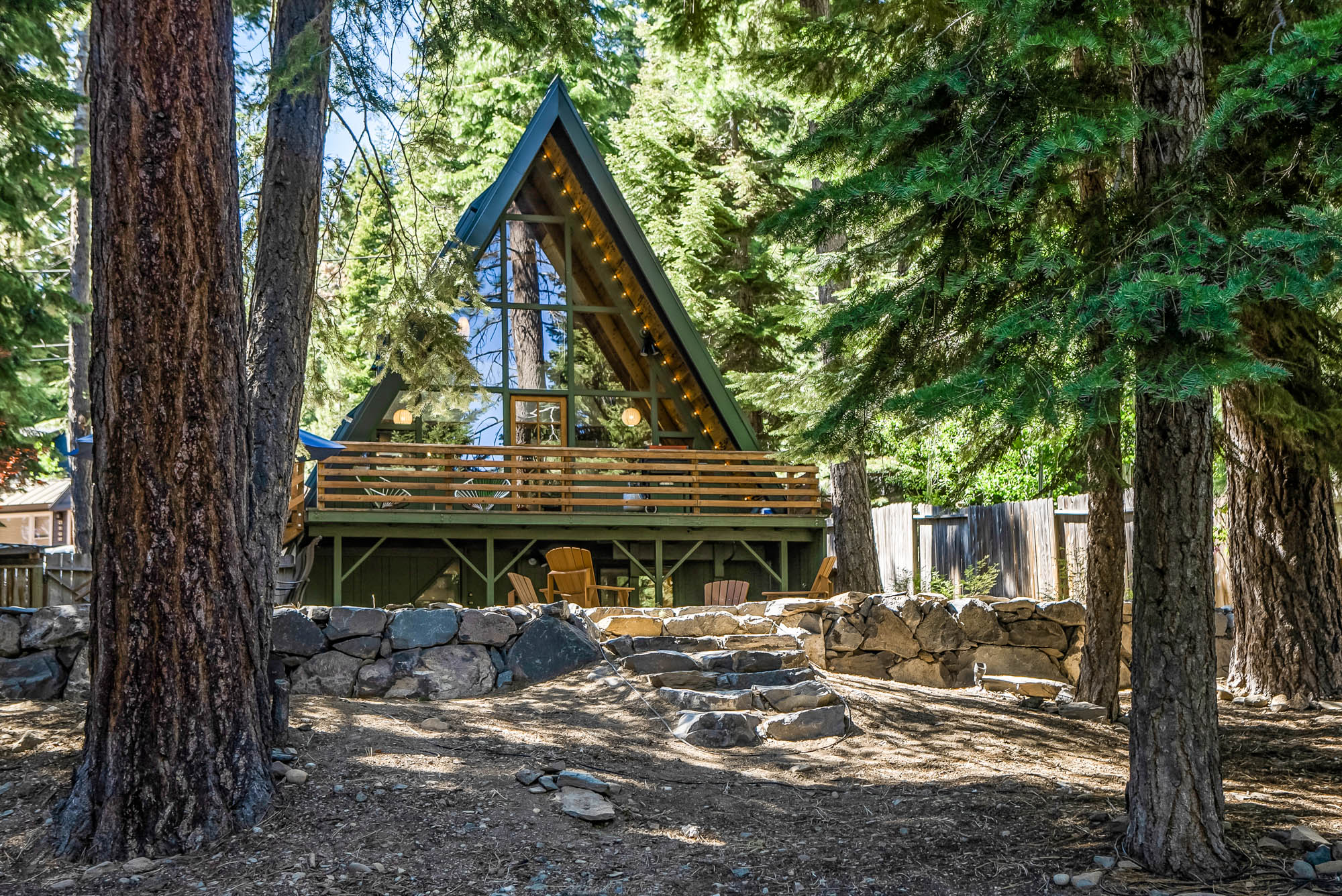 The A-Frame among the pines with its deck and fire pit