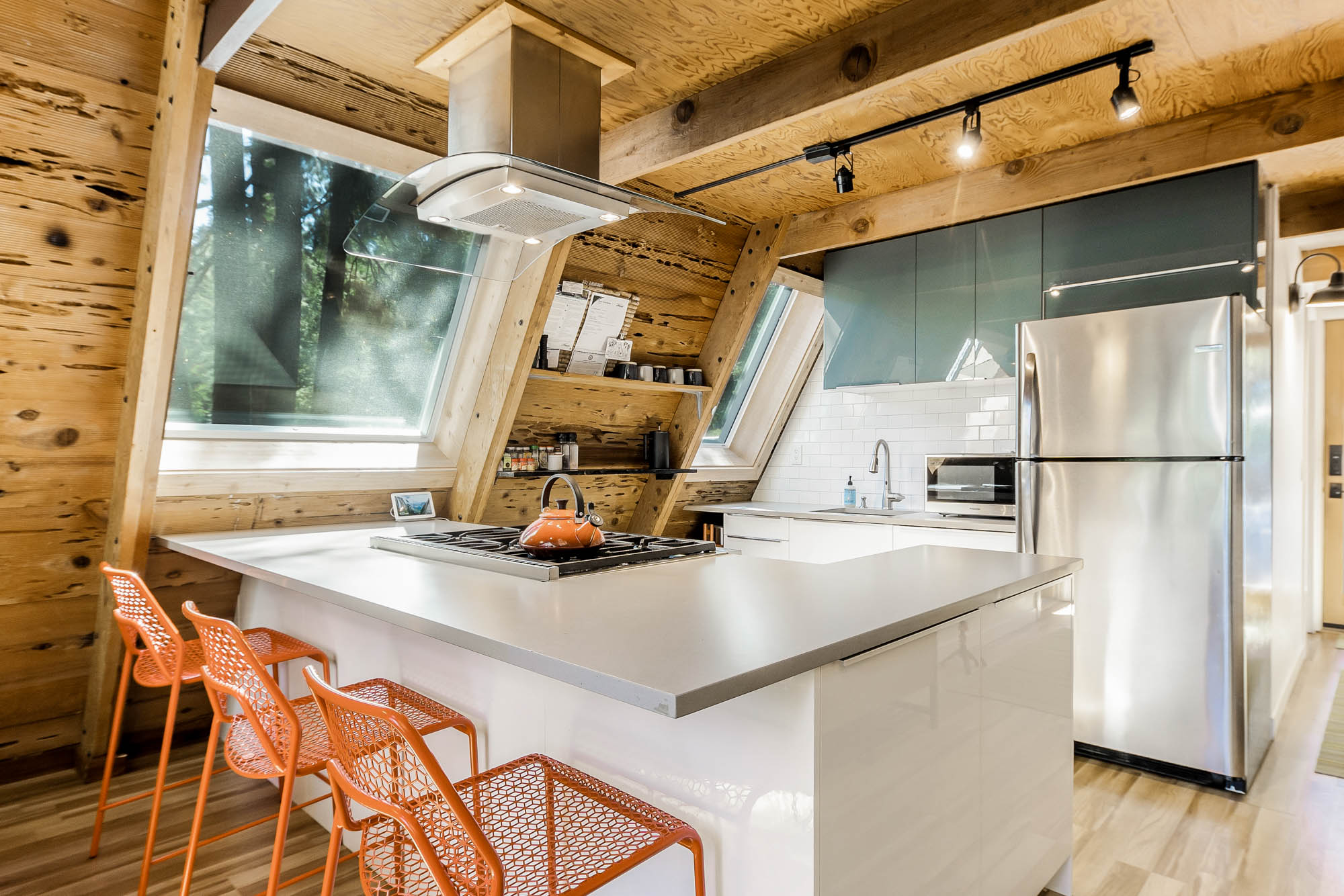 The open kitchen with orange stools and range hood